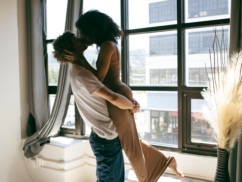 A man and a woman standing in front of a window